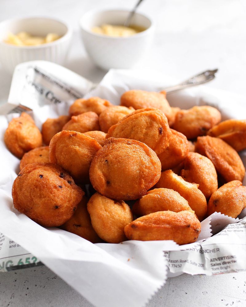 A basket of golden fried akara bean balls lined with newspaper
